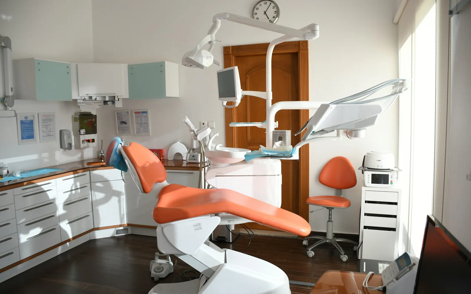 Pomarańczowy fotel dentystyczny i sprzęt stomatologiczny w jasnym gabinecie