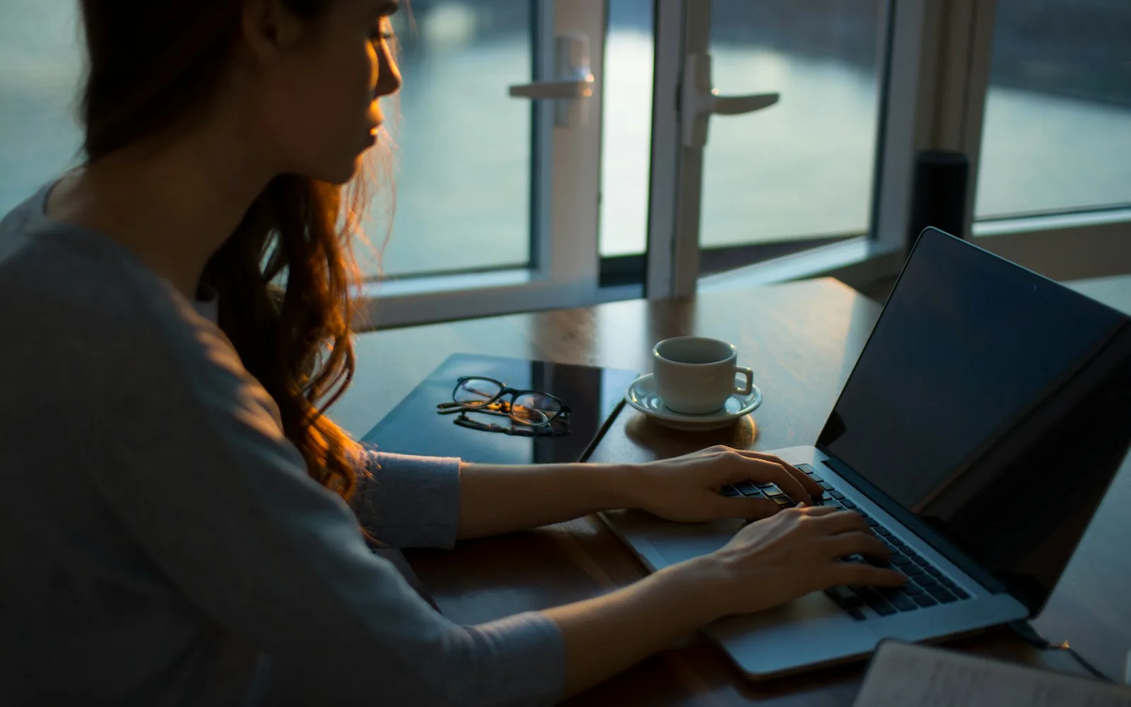 Kobieta pracuje przy laptopie przy stole w jasnym wnętrzu