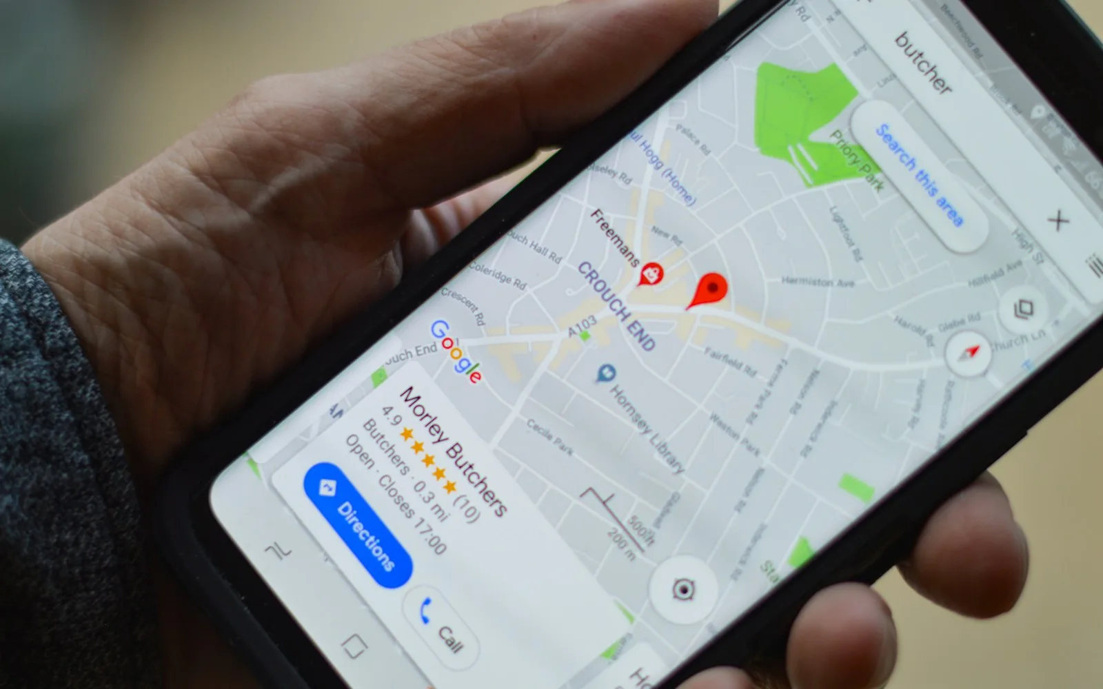 Smartfon z otwartą mapą Google i wizytówką lokalnej firmy w dłoni