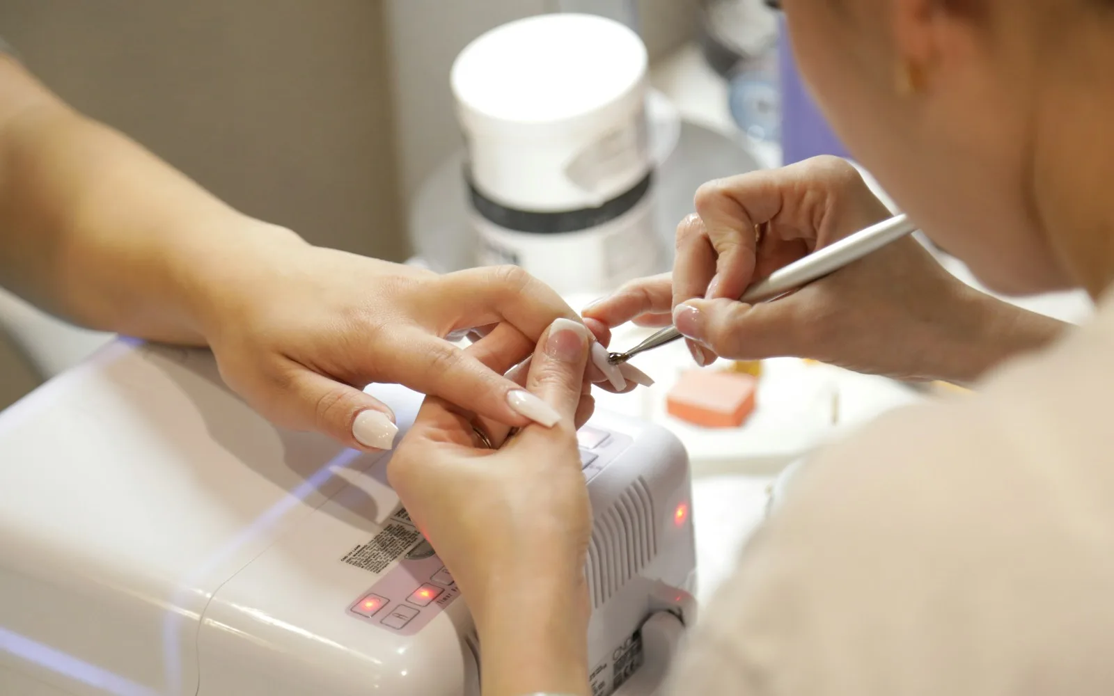 Stylistka paznokci wykonuje manicure klientce w salonie